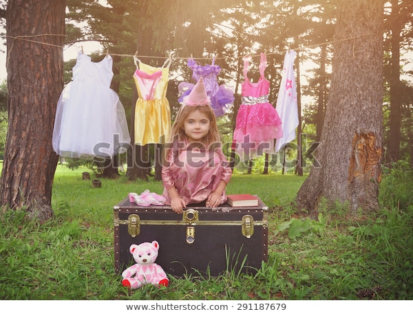 طفل صغير يتظاهر بأنه أميرة بالخارج حيث يرتدي ملابس معلقة على حبل للملابس لمفهوم الخيال أو الإبداع.